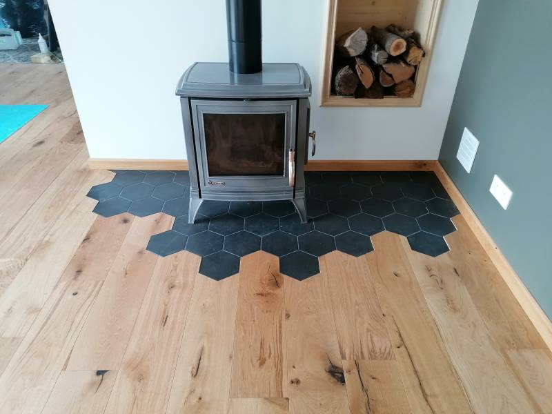 Pose de parquet flottant et carrelage autours d'un poêle à bois à Lyon dans un salon contemporain pour un rendu chaleureux